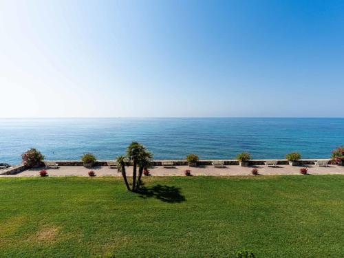 a palm tree in a field with the ocean in the background at Apartment Loggia sul mare by Interhome in Latte