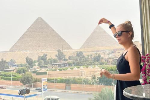 a woman standing in front of the pyramids at Unique Pyramids Boutique INN in Cairo