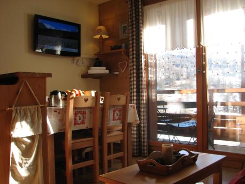 a living room with a table and chairs and a television at Appt Le Hameau Des Rennes 4 étoiles Pieds des pistes Piscine Intérieure Extérieure in Vars