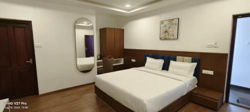 a bedroom with a white bed and a mirror at Raja Hill Resorts in Kodaikānāl