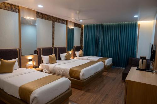 a hotel room with two beds and a television at THE GRAND ASTORIA SOMANTH by Shivalaya Darshanam in Somnath