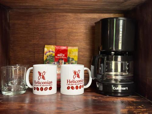 three coffee mugs sitting on a counter next to a coffee maker at Hotel Heliconias Nature Inn & Hot Springs in Fortuna