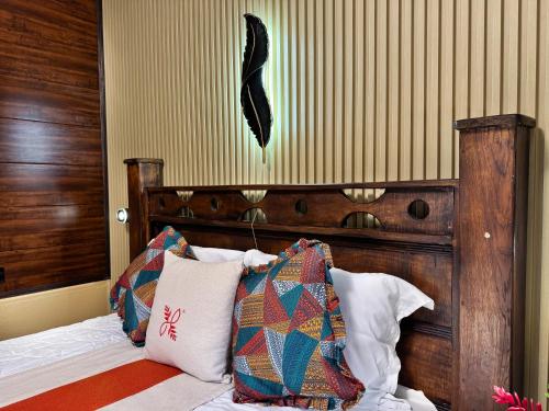 a bedroom with a bed with a wooden headboard and pillows at Hotel Heliconias Nature Inn & Hot Springs in Fortuna