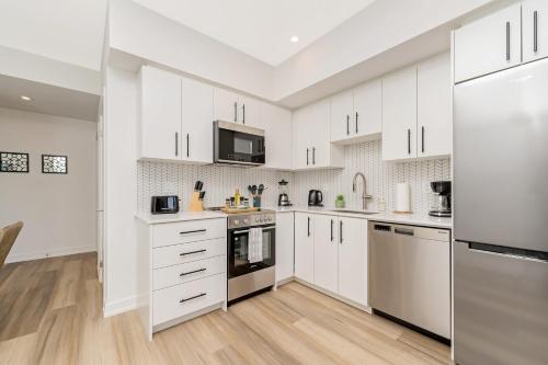 una cucina bianca con armadietti e elettrodomestici bianchi di Modern High Rise King bed Condo with Private Balcony a Kitchener