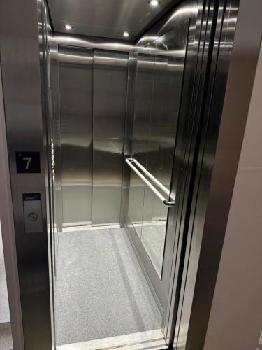 an elevator with a glass door with a stairway at Modern Central Apartment in Nitra
