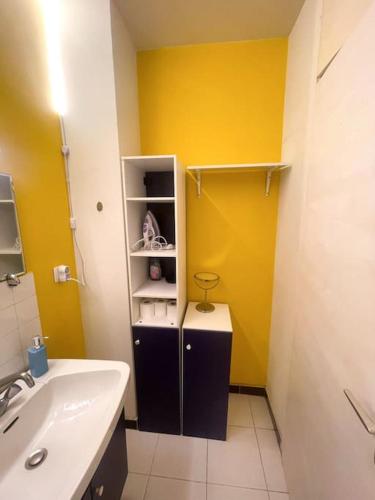 La salle de bains est pourvue d'un lavabo et d'un mur jaune. dans l'établissement Geneva Residences - Colourful Apartment by the border, à Ferney-Voltaire