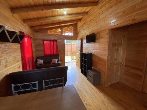 a living room with a couch and a room with wooden walls at Cabaña Tulipanes - COZY cabin in an awesome place! in Jardín