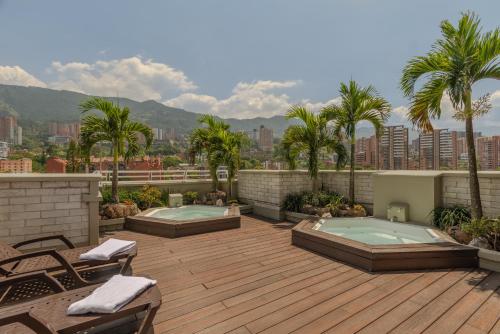a patio with two hot tubs on a roof at Hotel Poblado Alejandria in Medellín