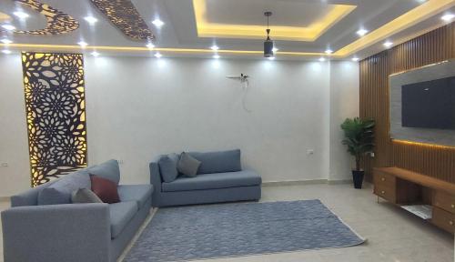 Una sala de estar con dos sofás y un televisor de pantalla plana. en فيلا نون, en El Cairo