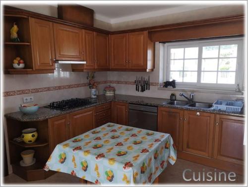 a kitchen with wooden cabinets and a table with a towel on it at Foz do Arelho dans un cadre paradisiaque in Foz do Arelho