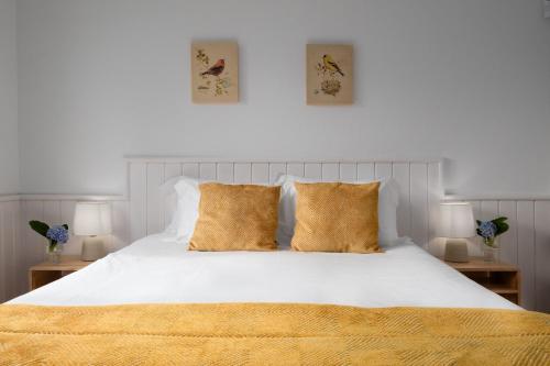 a bedroom with a white bed with gold pillows at Serenity Villa in Mosteiros