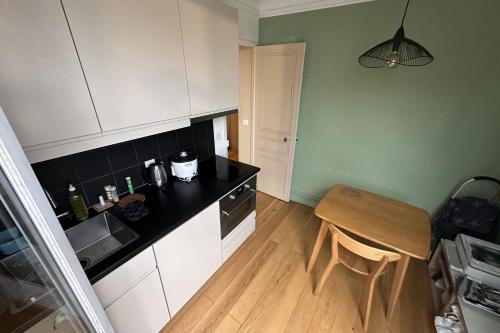 Elle comprend une petite cuisine avec des placards blancs et une table en bois. dans l'établissement Beautiful T2 with balcony - near Parc Clichy, à Paris