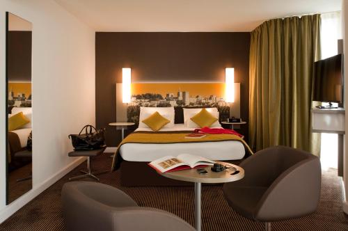 a hotel room with a bed and a table and chairs at Mercure Avignon Centre Palais des Papes in Avignon