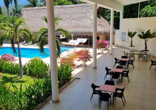 a patio with tables and chairs next to a pool at HOTEL SANTAFE NATURA - SANTAFE DE ANTIQUIA in Santa Fe de Antioquia