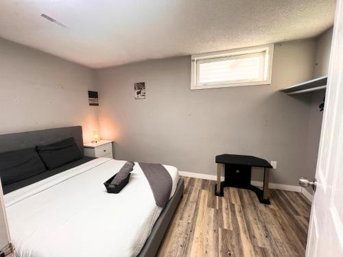 a bedroom with a bed and a window and a table at Flowealth Suites - Private Rooms Near West Edmonton Mall in Edmonton