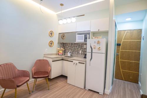 a kitchen with a white refrigerator and two chairs at Hortênsia Confort Stúdio Rio in Rio de Janeiro