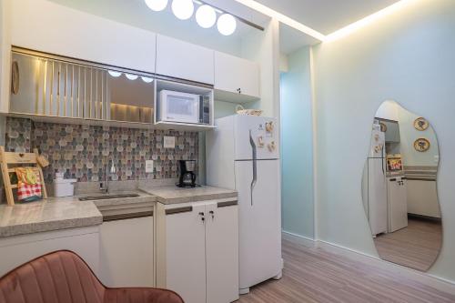 a kitchen with white cabinets and a white refrigerator at Hortênsia Confort Stúdio Rio in Rio de Janeiro