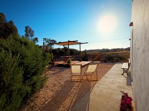 a patio with a table and chairs and an umbrella at Monte Paxôra in Rogil