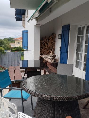 une terrasse avec une table et des chaises ainsi qu'une pile de bûches dans l'établissement Maison Biziari, à Urrugne
