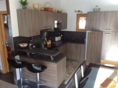 une cuisine avec des placards en bois et des comptoirs noirs dans l'établissement Appartement Duplex 3 Chambres pour 6 Personnes avec Balcon à Valloire, 400m des Pistes - FR-1-263-297, à Valloire