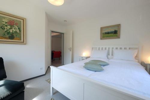 a white bedroom with a white bed with two pillows at Appartement da Käthy à Grono Val Mesolcina in Grono