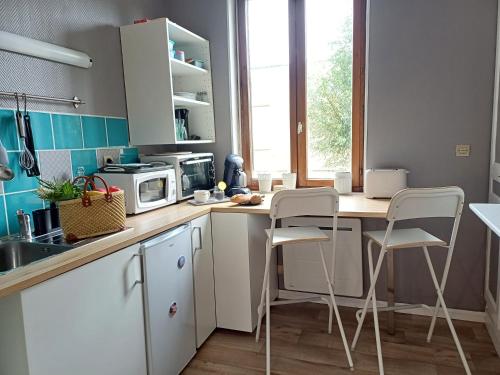 une cuisine avec des armoires blanches et une table et des chaises dans l'établissement Archer 1er, Plein centre, quartier historique, à Amiens