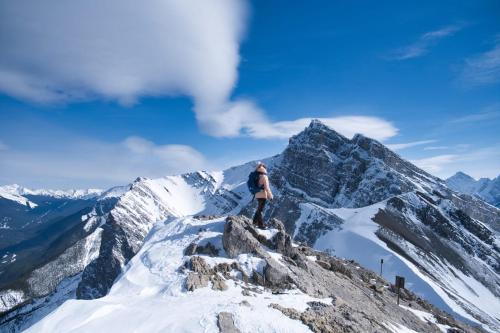 a man standing on the top of a mountain at Special! New Downtown Mtn View Free Parking 2b&2b in Canmore