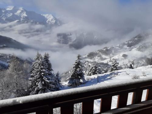 - une vue sur une montagne enneigée avec des arbres et des nuages dans l'établissement Vue et Soleil Alpe d'Huez, à Huez