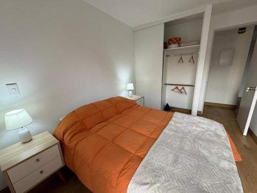 a bedroom with a large bed with an orange blanket at Cómodo y Acogedor Departamento Cerca de Barranco y el Circuito de Playas in Lima