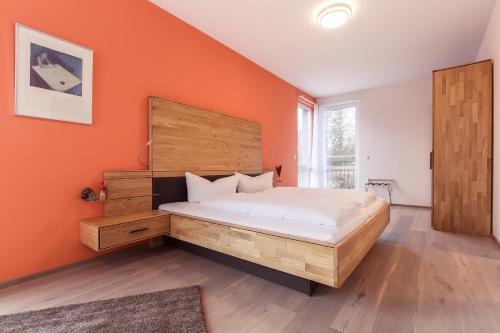 ein Schlafzimmer mit einem großen Bett und einer orangefarbenen Wand in der Unterkunft Hotel Vier Jahreszeiten an den Thermen in Bad Krozingen