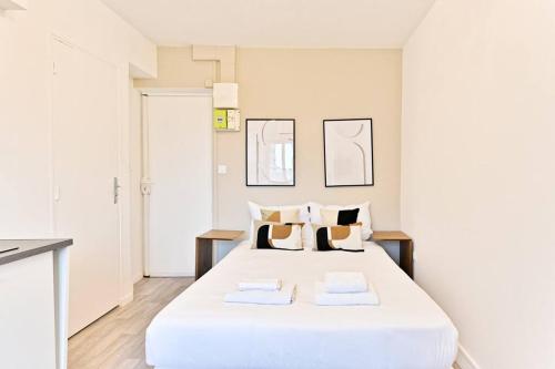 une chambre avec un grand lit blanc avec deux oreillers dans l'établissement Petit Studio chaleureux en Banlieue - Asnières, à Asnières-sur-Seine