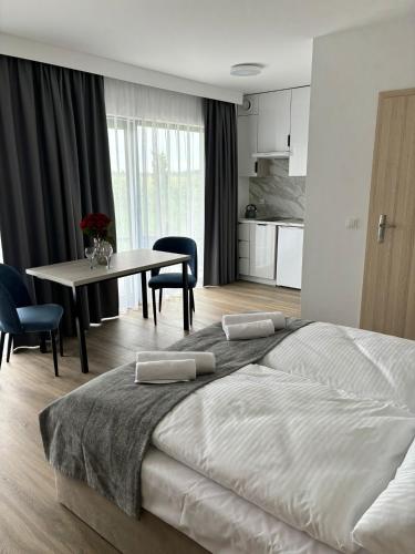a bedroom with a large bed and a table with chairs at Hotel i Apartamenty Gorzelanny Dźwirzyno in Dźwirzyno