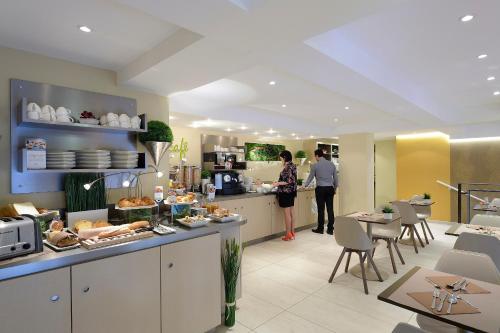 a kitchen with two people standing in the kitchen at Mercure Avignon Centre Palais des Papes in Avignon
