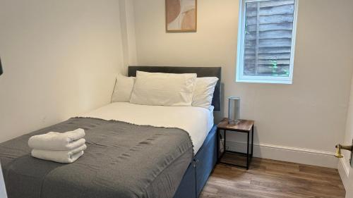 a small bedroom with a bed with white sheets and a window at 4Bedroom house at Town Centre with Free Driveway Parking in Buckinghamshire
