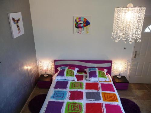 Dormitorio con cama con colcha y almohadas coloridas en La Bastide Des Selves, en Draguignan