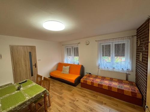a living room with an orange couch and a bed at Apartmán pod kostelem in Strážov