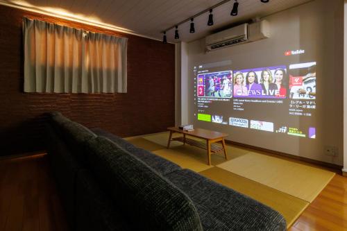 a living room with a couch and a large screen at Bliss KAMEARI in Tokyo