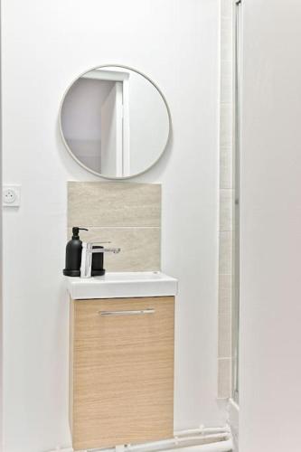 une salle de bain avec un lavabo et un miroir dans l'établissement Petit studio équipée en banlieue Parisienne, à Asnières-sur-Seine