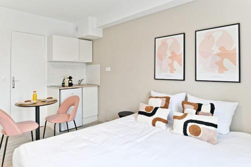 une chambre blanche avec un lit, une table et des chaises dans l'établissement Petit studio équipée en banlieue Parisienne, à Asnières-sur-Seine