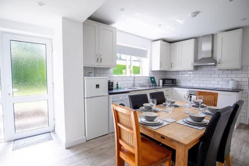 a white kitchen with a wooden table and chairs at SHELTER STONE - Cottage in the heart of the Lakes in Keswick