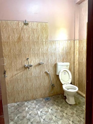 a bathroom with a toilet and a shower at Tree Tops Retreat B&B in Sauraha