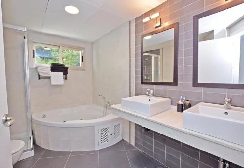 a bathroom with two sinks and a tub and a mirror at Villa Entre Rocas in Zahara de los Atunes