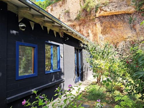 une maison noire avec des fenêtres bleues à côté d'une montagne dans l'établissement La Cabane des Dunes, à Poitiers