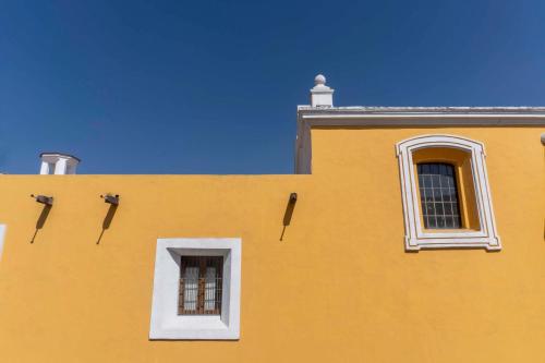 a yellow building with two windows and a roof at Palacio Julio Hotel in Puebla