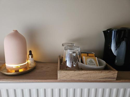 a table with a lamp and a candle on a shelf at Buteo chambres d'hôtes & espresso in Lesterny