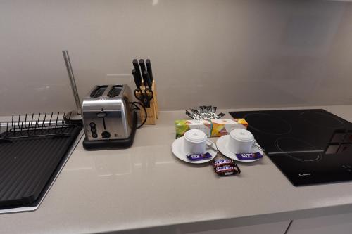 a counter with two coffee cups and a toaster at Address Residence Bahrain in Rayyā