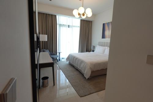 a hotel room with a bed and a desk and a window at Address Residence Bahrain in Rayyā