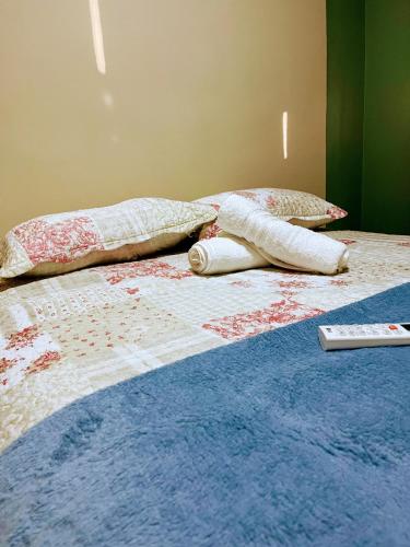 a bed with two pillows and a remote control on it at Impera House 2 km do centro in Imperatriz