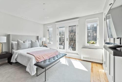 a white bedroom with a bed and windows at Luxe Studio with Charming Juliet Balcony in New York