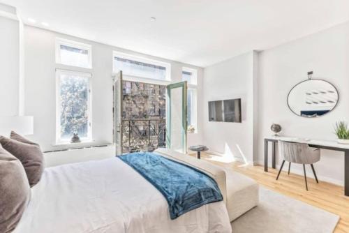 a white bedroom with a bed and a desk at Studio w Charming Juliet Balcony in Upper East in New York